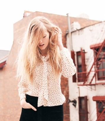 He takes Louise's hair and begins to cut long layers at the ends with scissors.